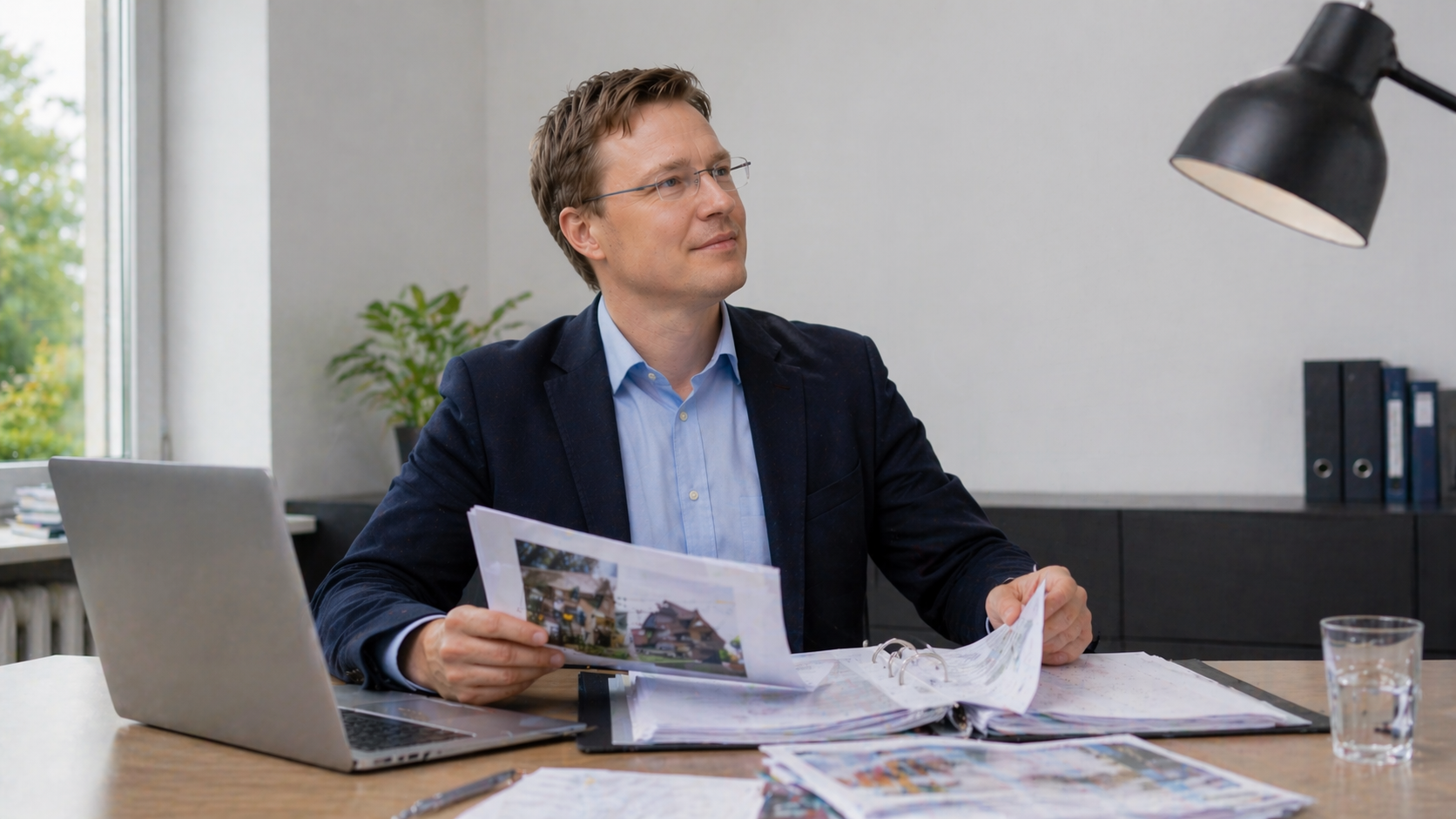Immobiliengutachter analysiert strukturiertes Verkehrswertgutachten in Hannover mit Unterlagen und Laptop